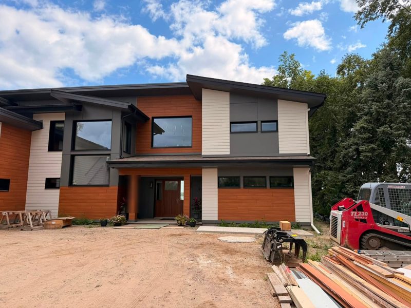 Modern two-story house with orange and grey siding and dark gutters along the roof edges