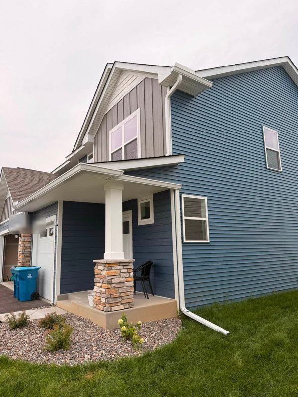 Blue house with a stone-based porch column and white gutters and downspouts