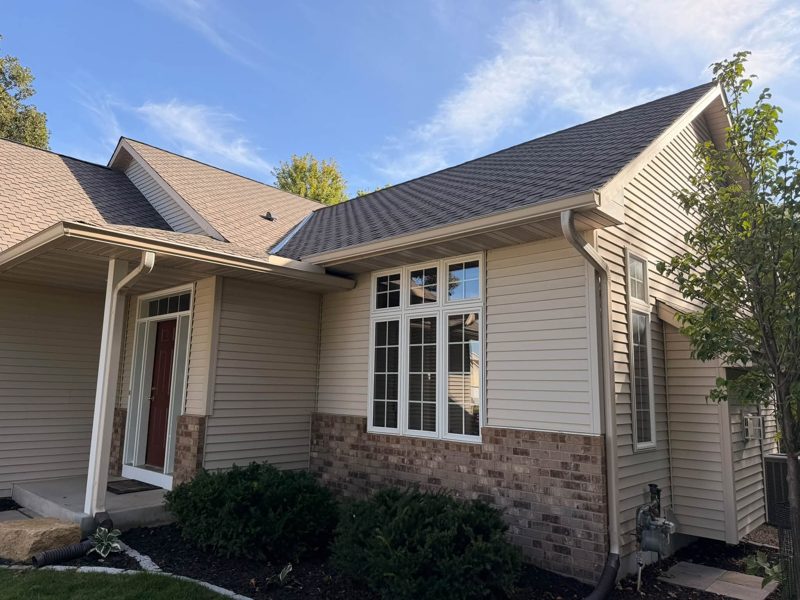 Tan ranch house with brick below the windows and gutters along the front roof lines